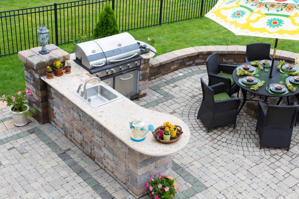 luxury outdoor kitchen with a grill station and decorative brick patio
